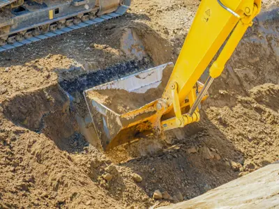 an excavator bucket pulling dirt from the ground