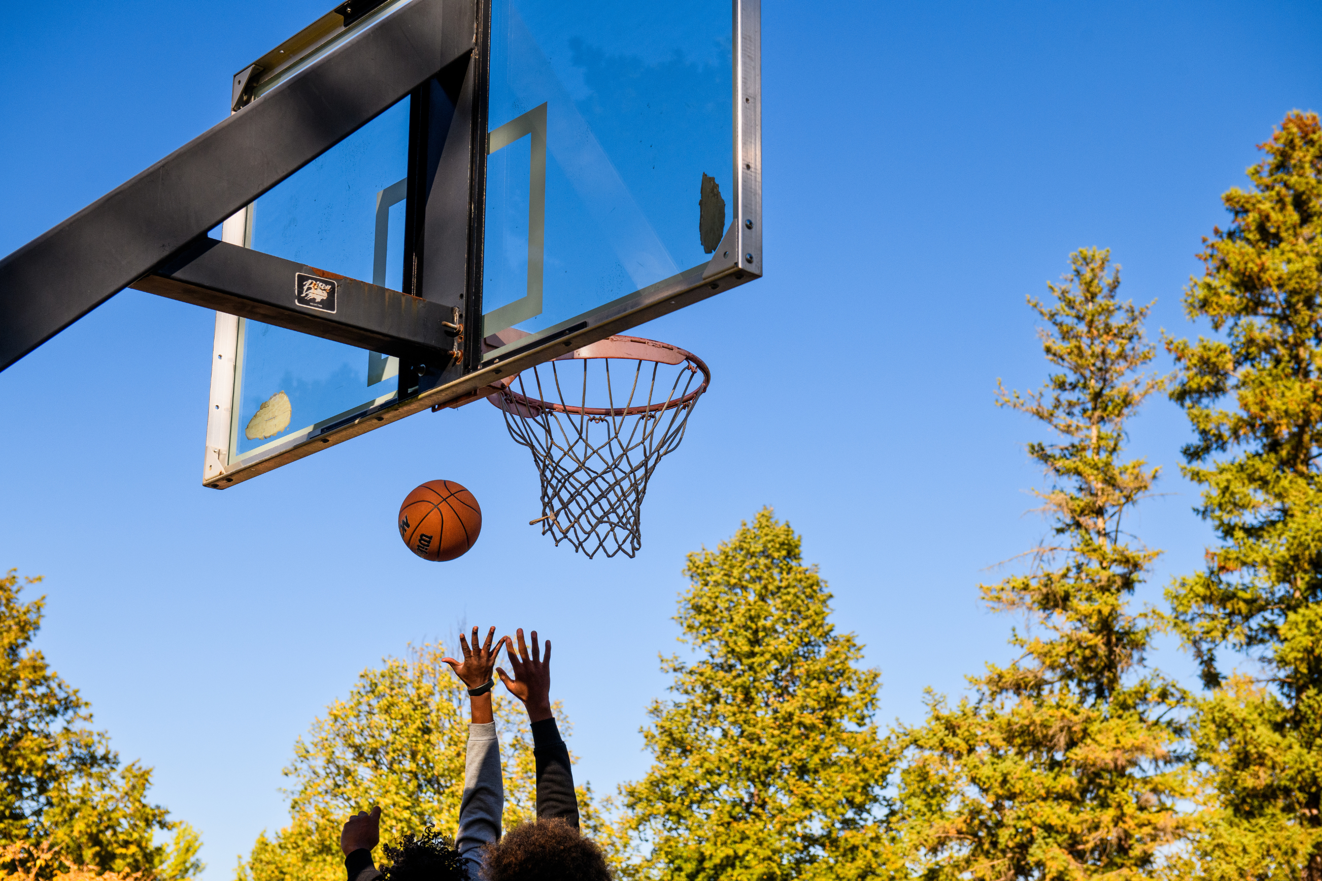 a basketball approaching a basketball hoop at an outside court