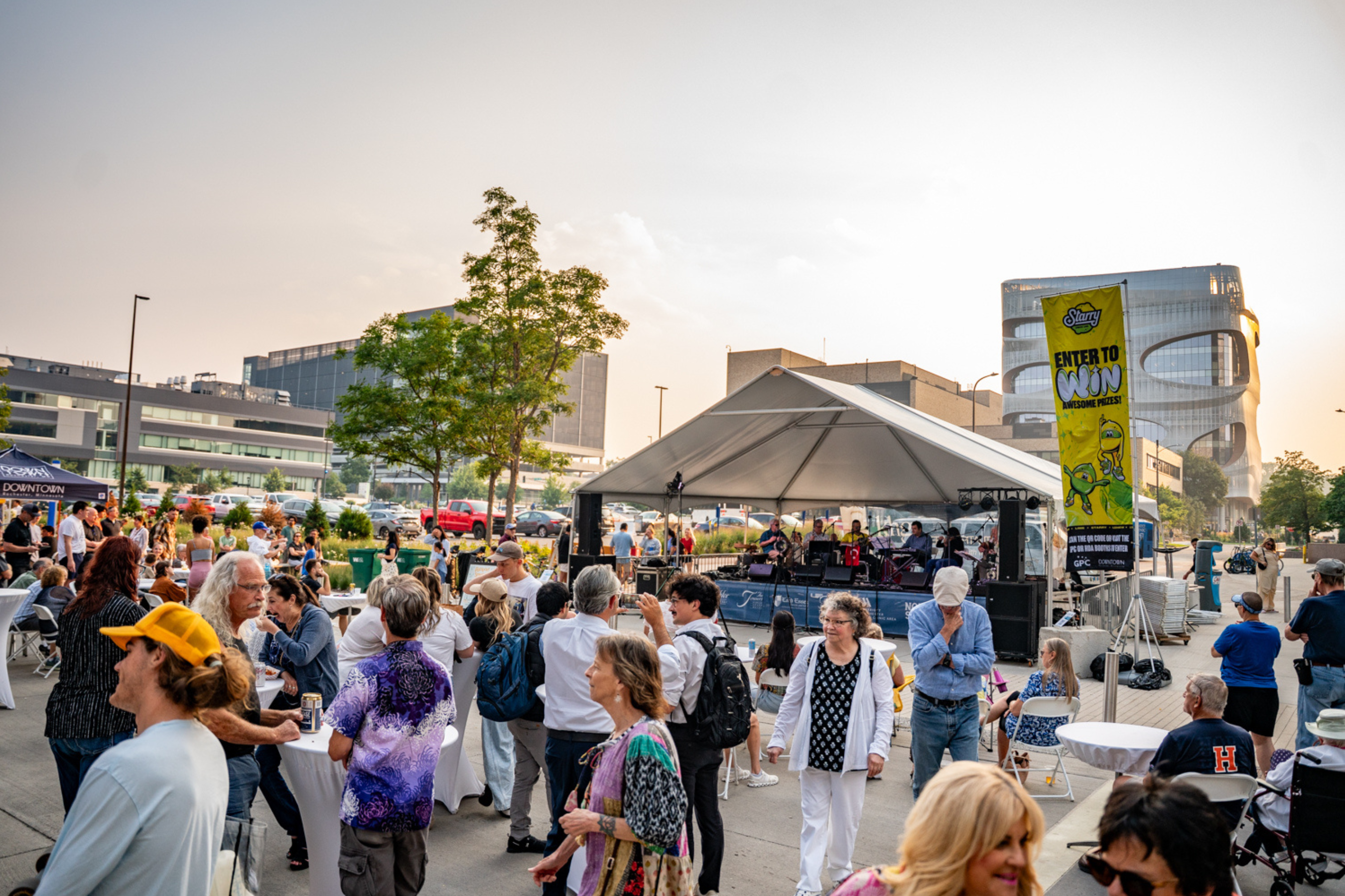 a crowd of people gathered at an outdoor stage just before sunset