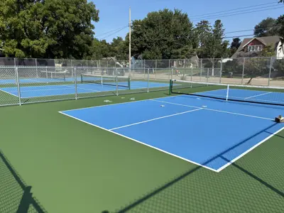 Newly reconstructed pickleball courts at Cook Park featuring blue and green playing surfaces, white court lines, nets and surrounding fencing.