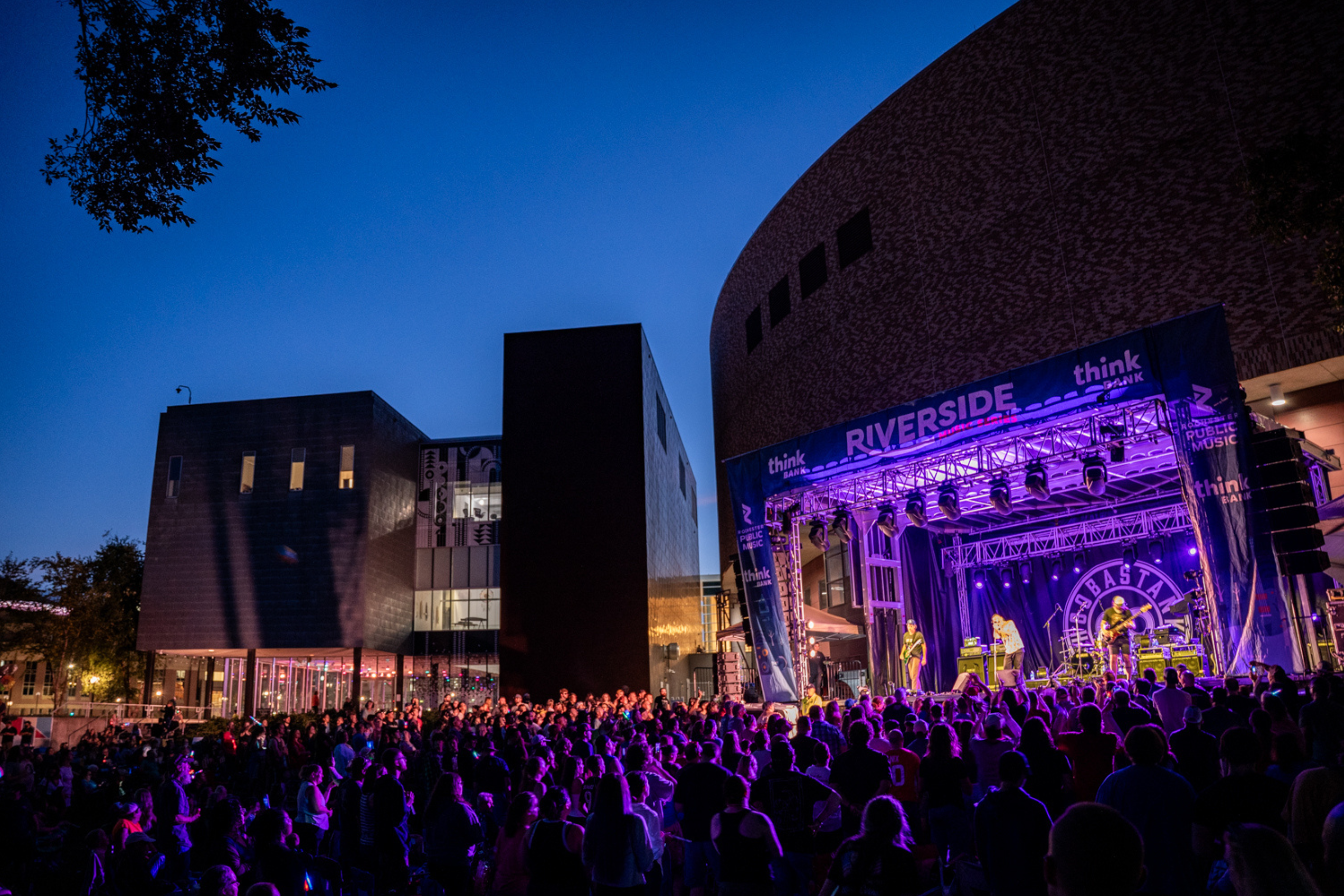 a crowed of people glowing in the lights of a stage that says 'riverside'