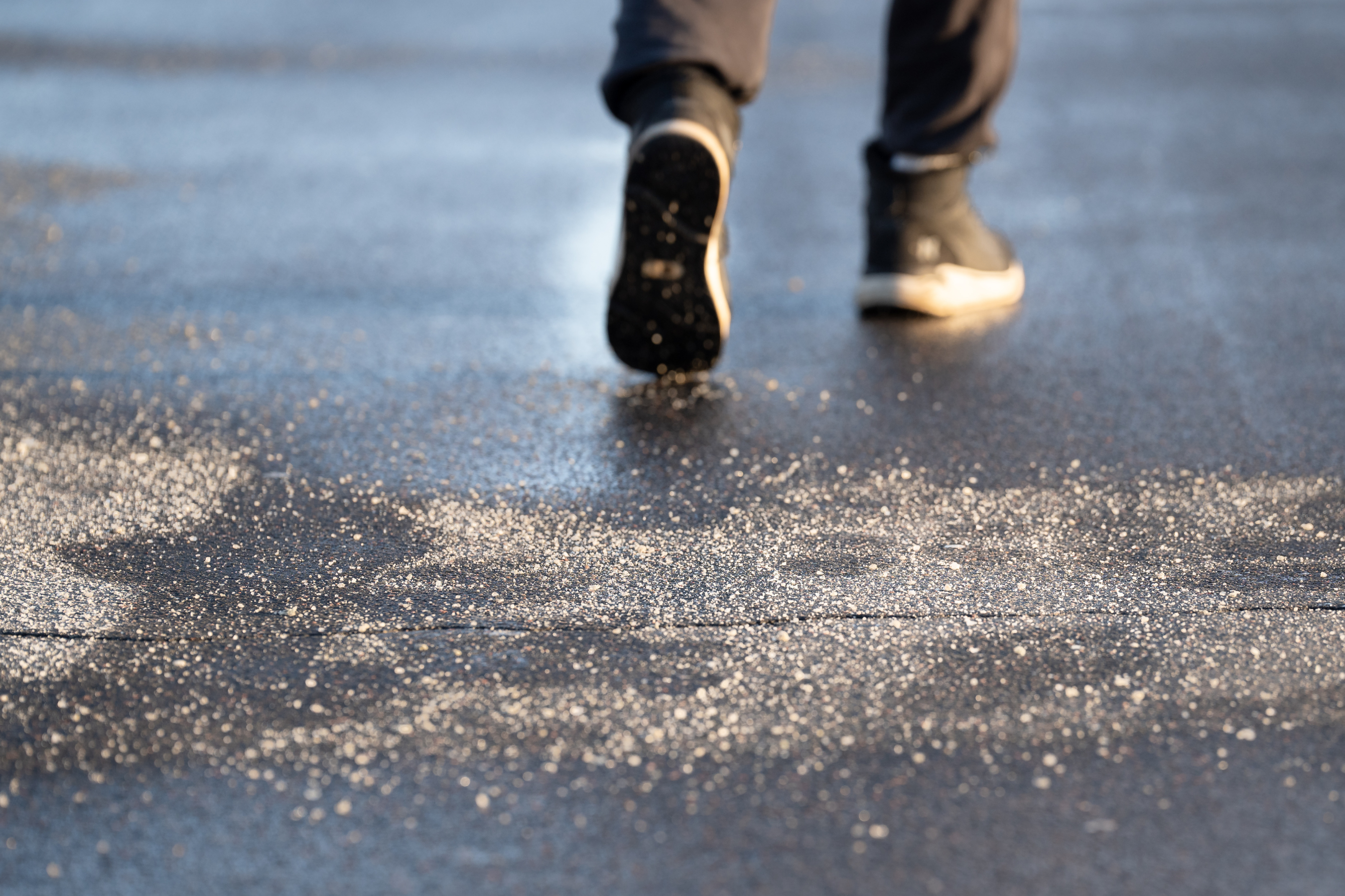 a sidewalk with salt sprinkled on top and two feet walking across it