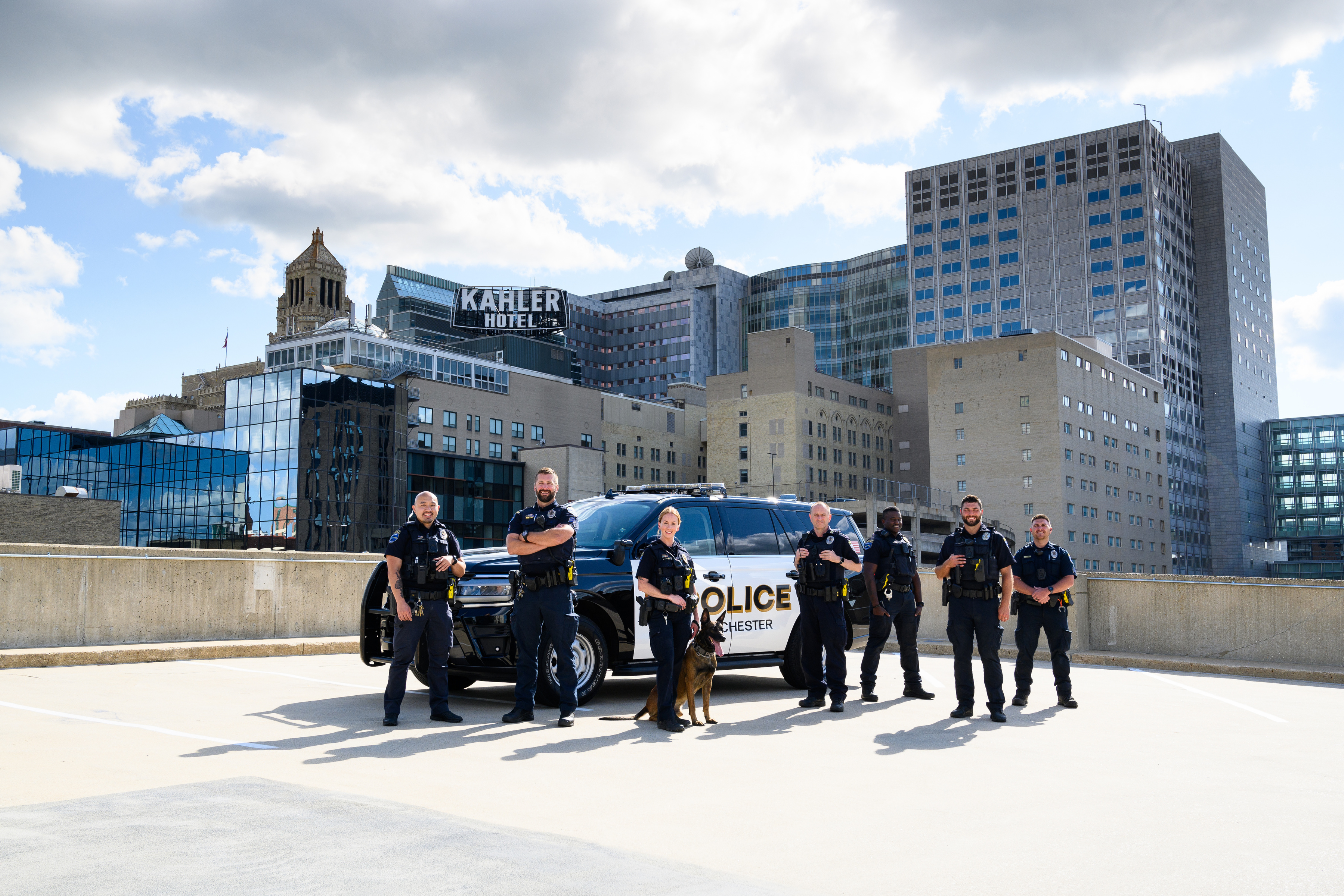 a group of seven police officers and a k9 standing in front of a police car