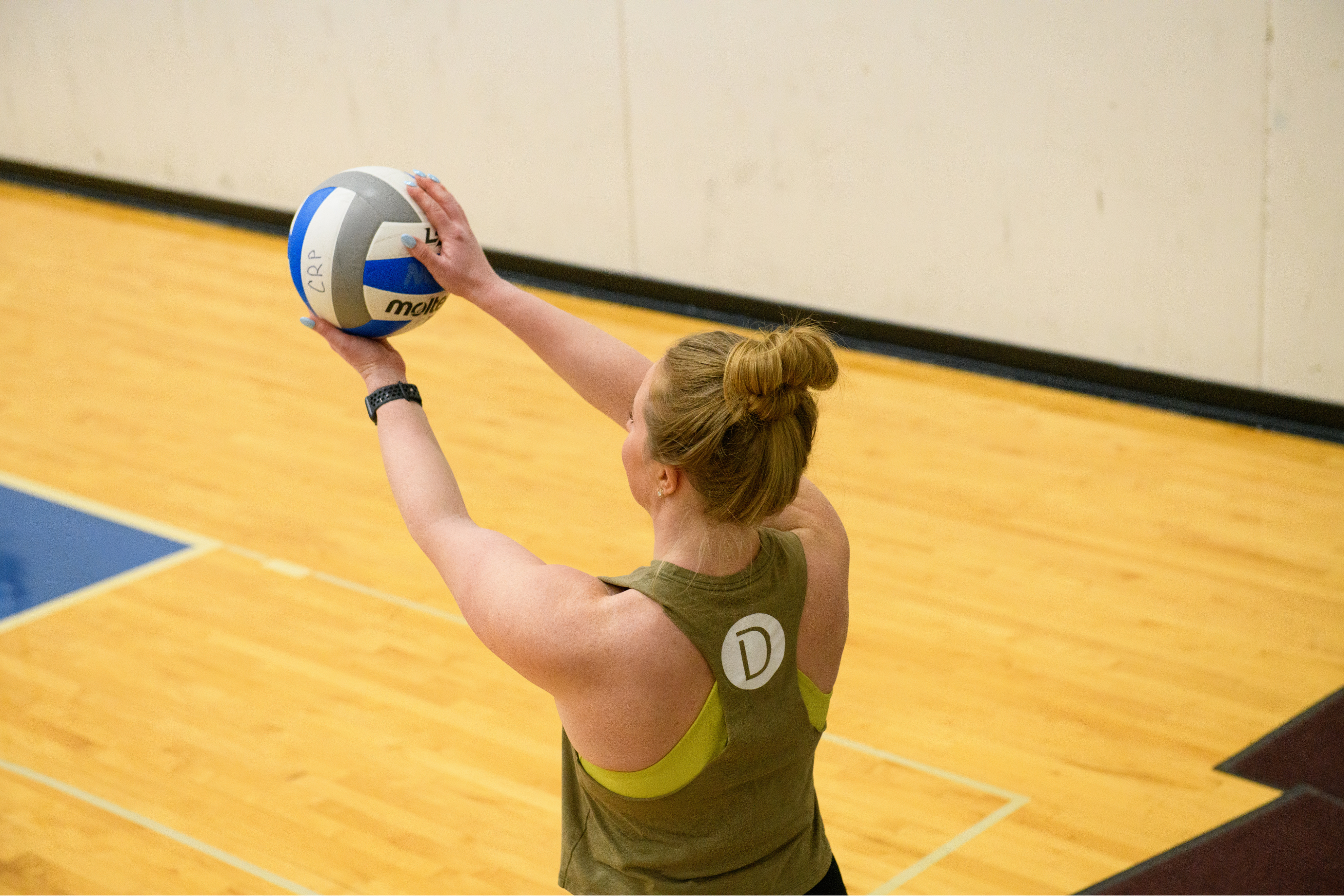a woman preparing to serve a volleyball at an indoor court