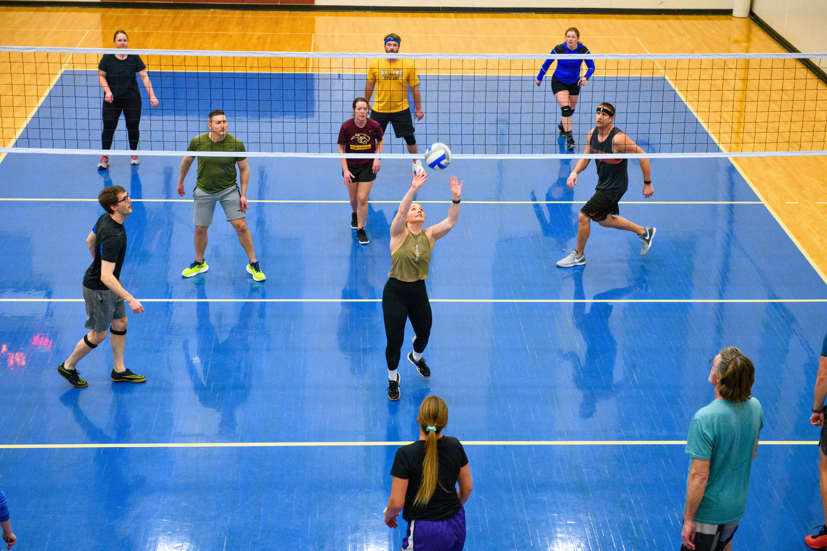 Two teams of six playing casual volleyball at an indoor court. photo taken from above.