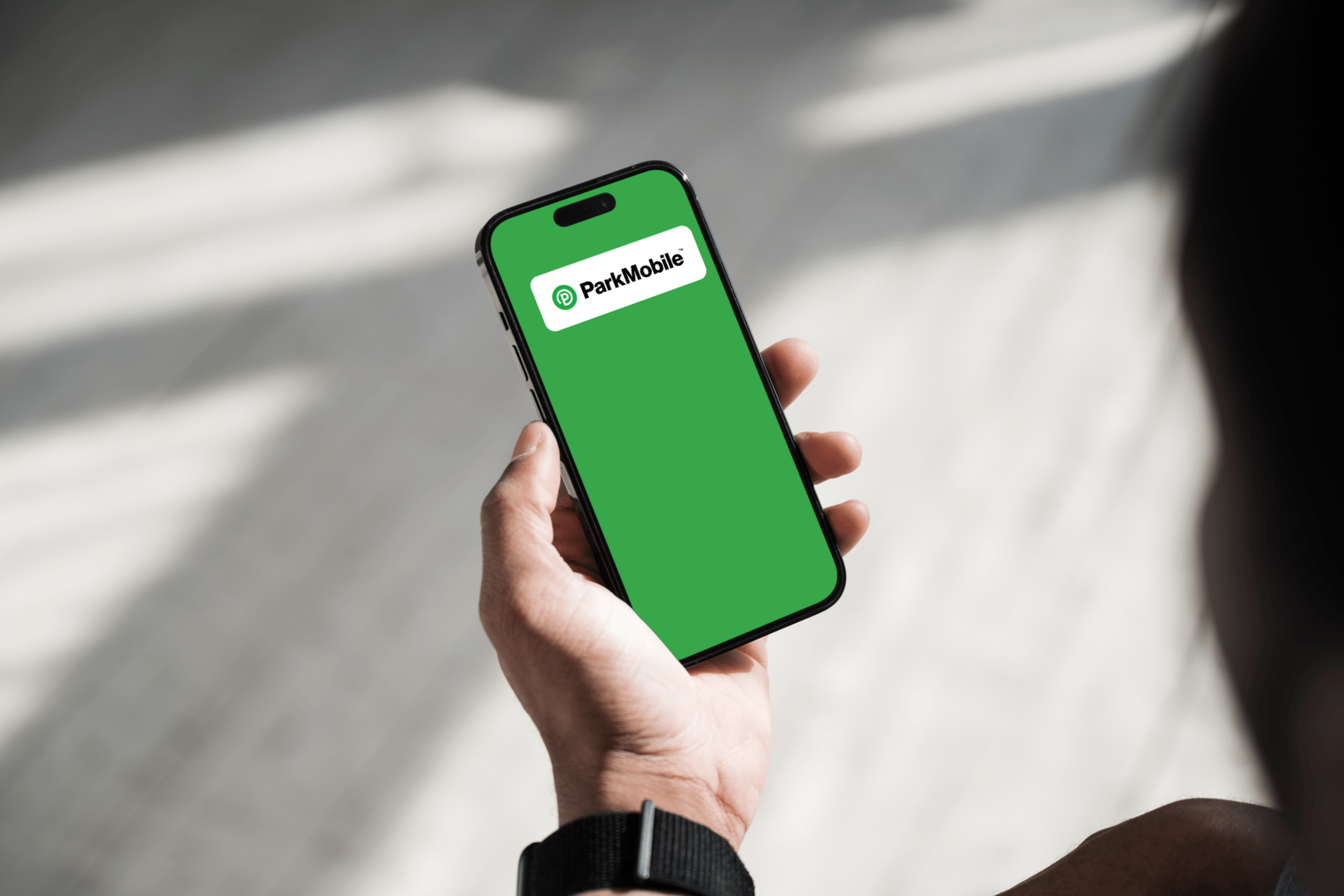 a hand holding a smart phone with 'park mobile' on the screen