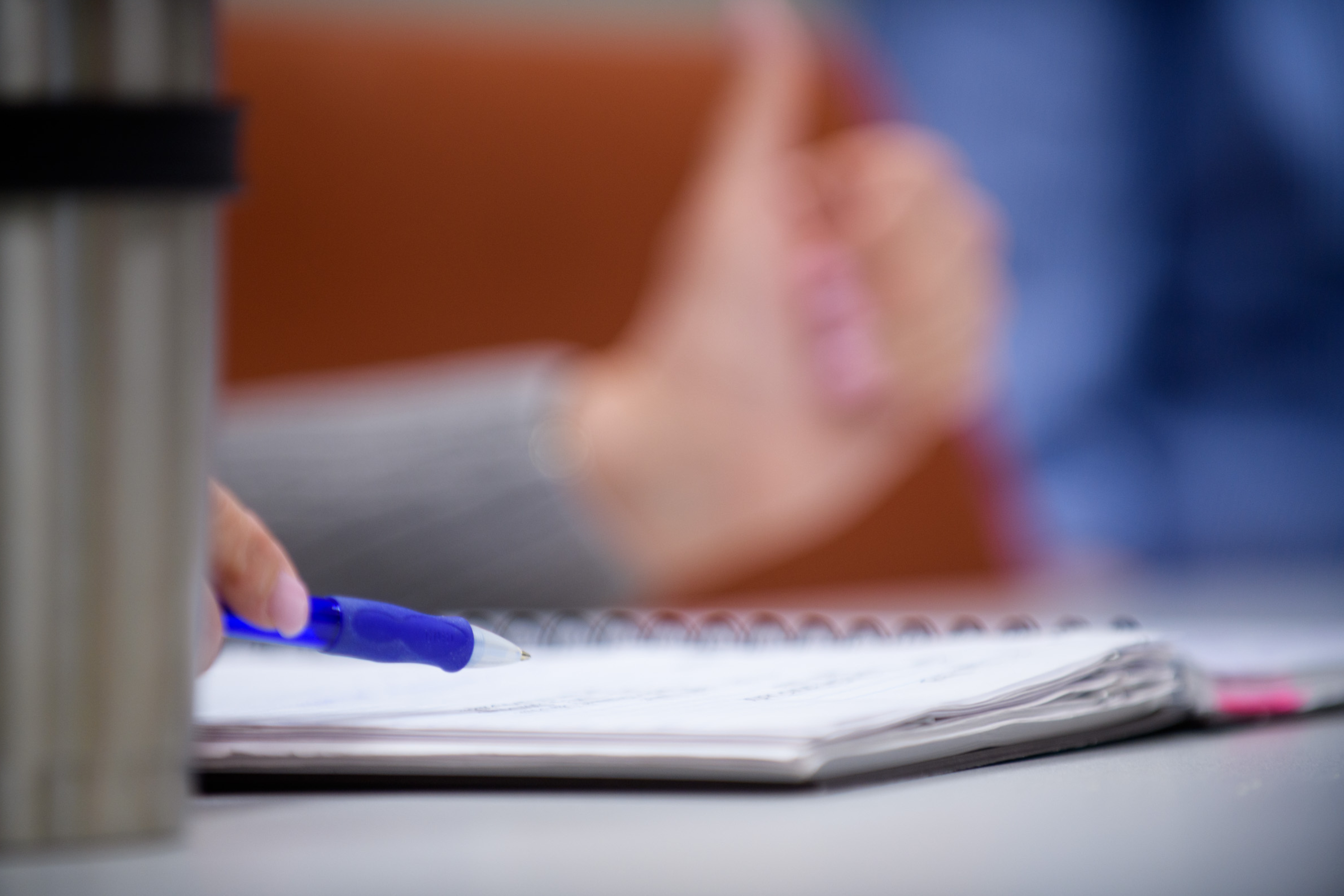 close up view of a notebook and someone holding a pen near it