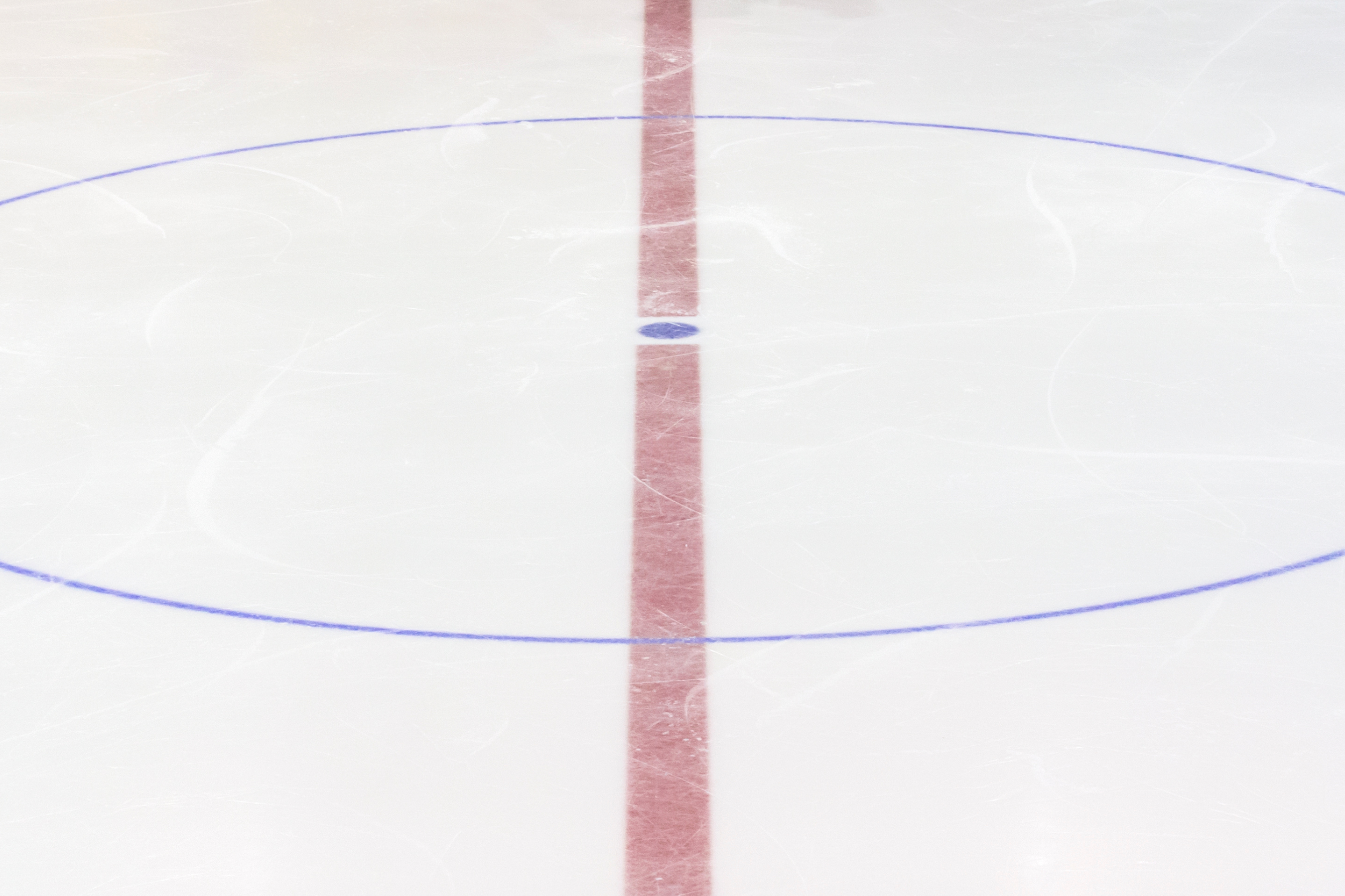 close up of red line and blue circle on an ice rink