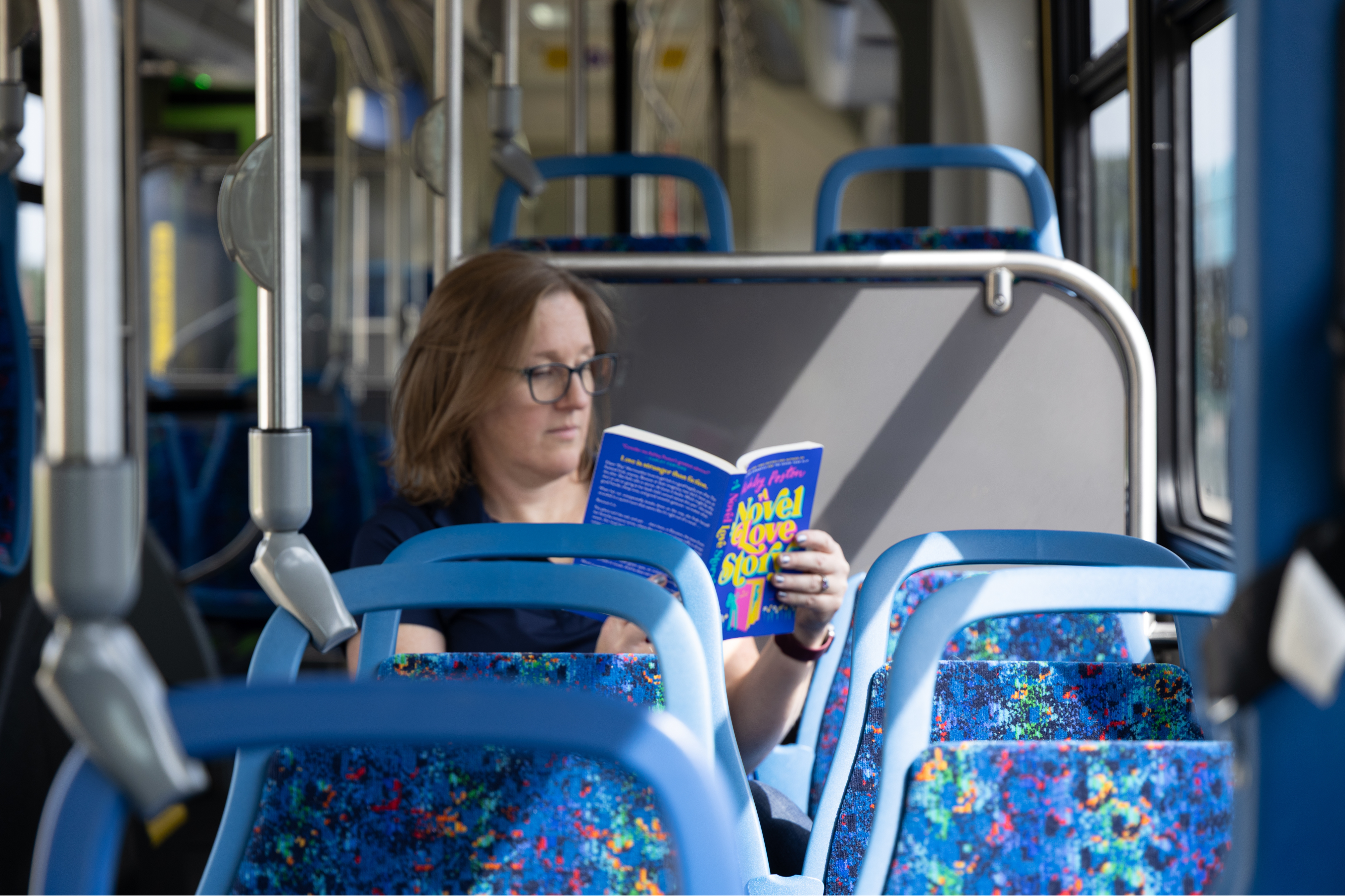 a woman riding a city bus and reading a book