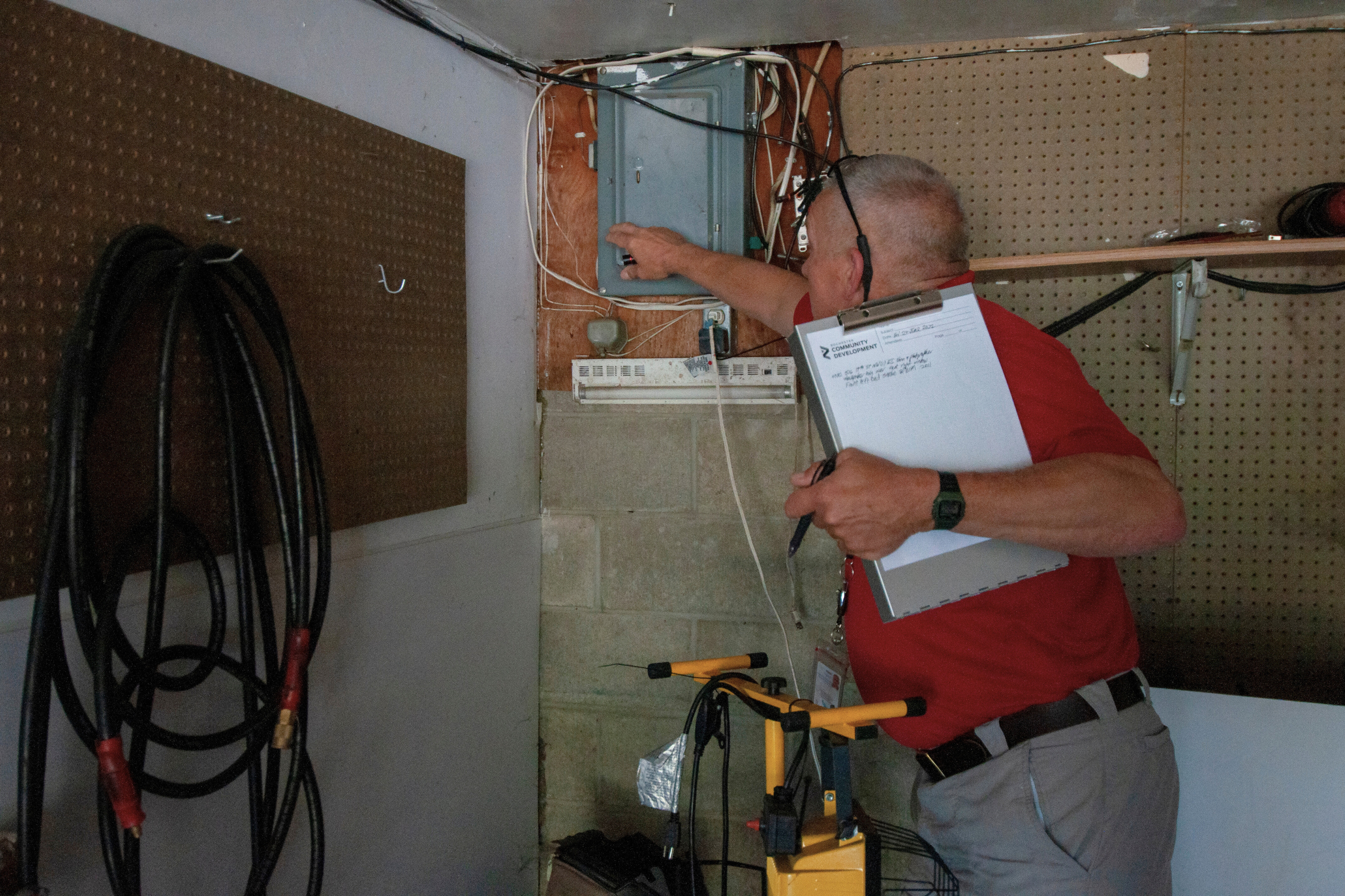 an inspector with a clipboard examining an electrical panel