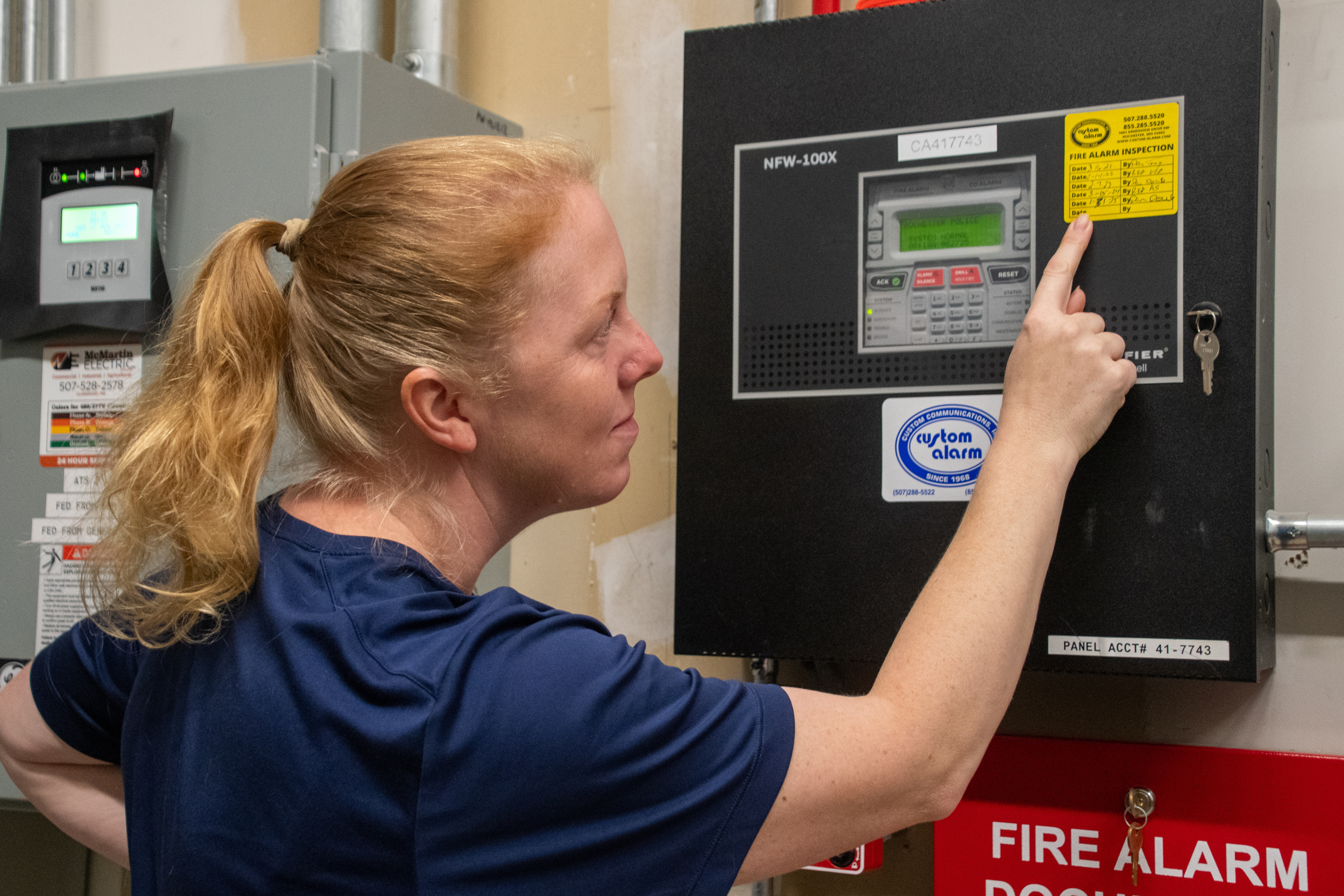 a woman pointing and looking at a sticker on an alarm panel