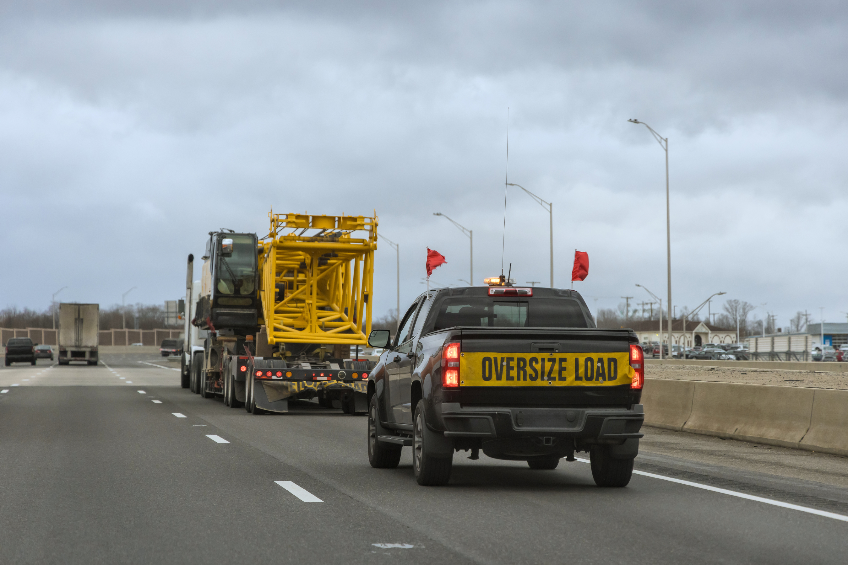 a large apparatus on the highway followed by a truck with an 'oversize load' sign