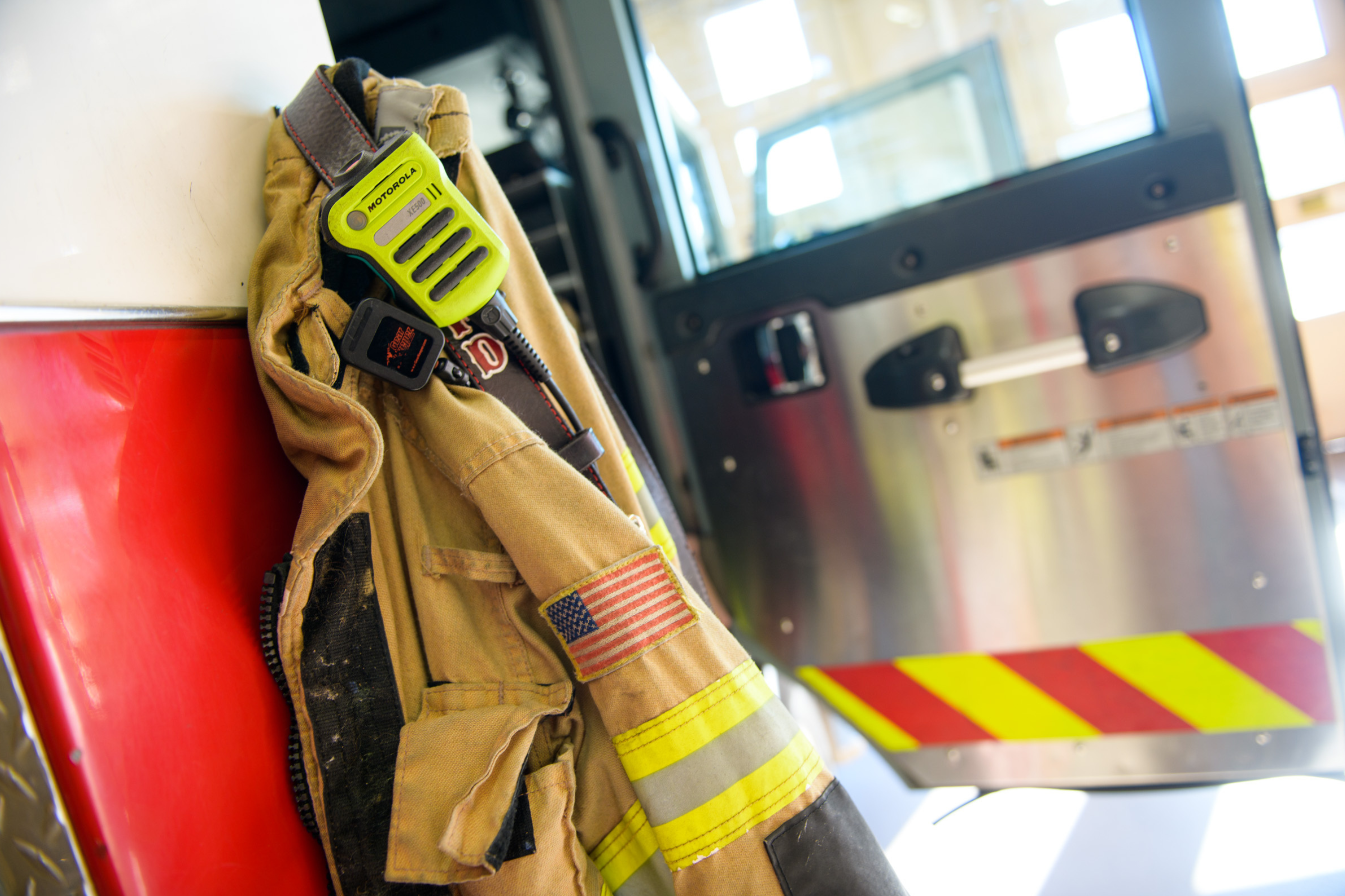 a firefighter jacket and walkie hung on the outside of a fire engine