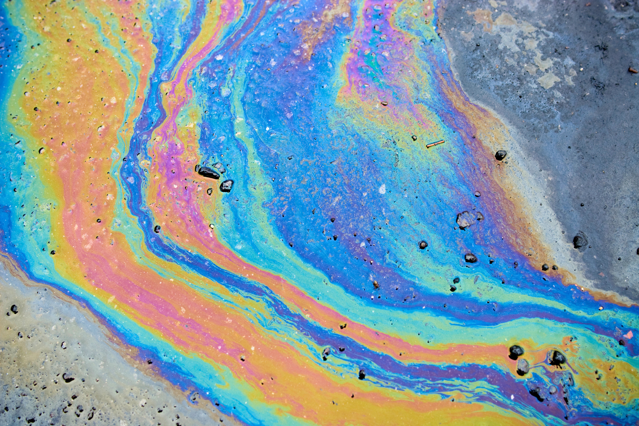spilled oil on a flat surface displaying blue orange and red hues