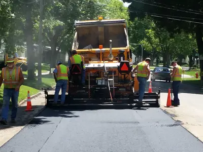 Heavy equipment and construction workers laying new pavement