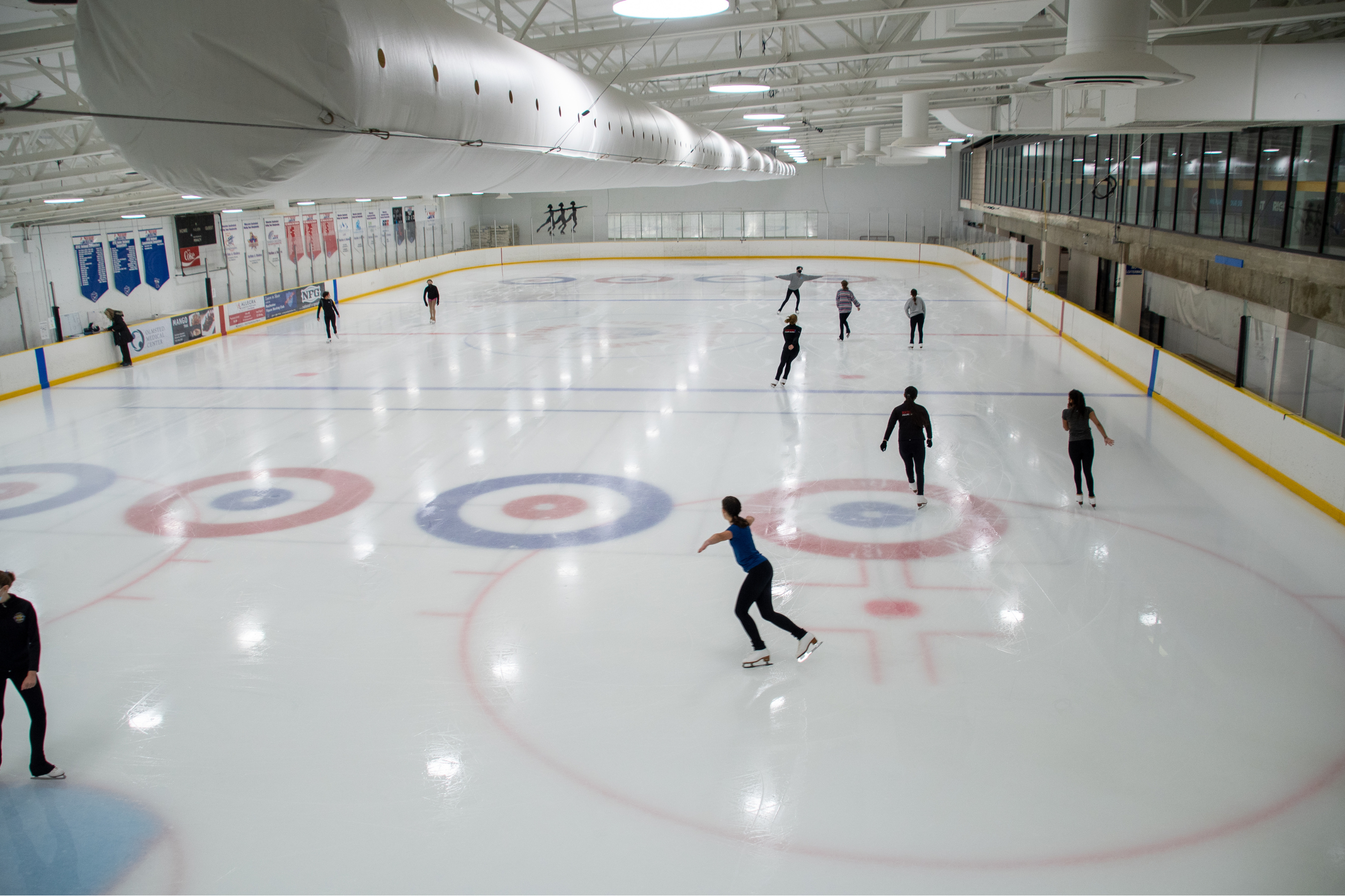 several people ice skating during open skate at an indoor rink