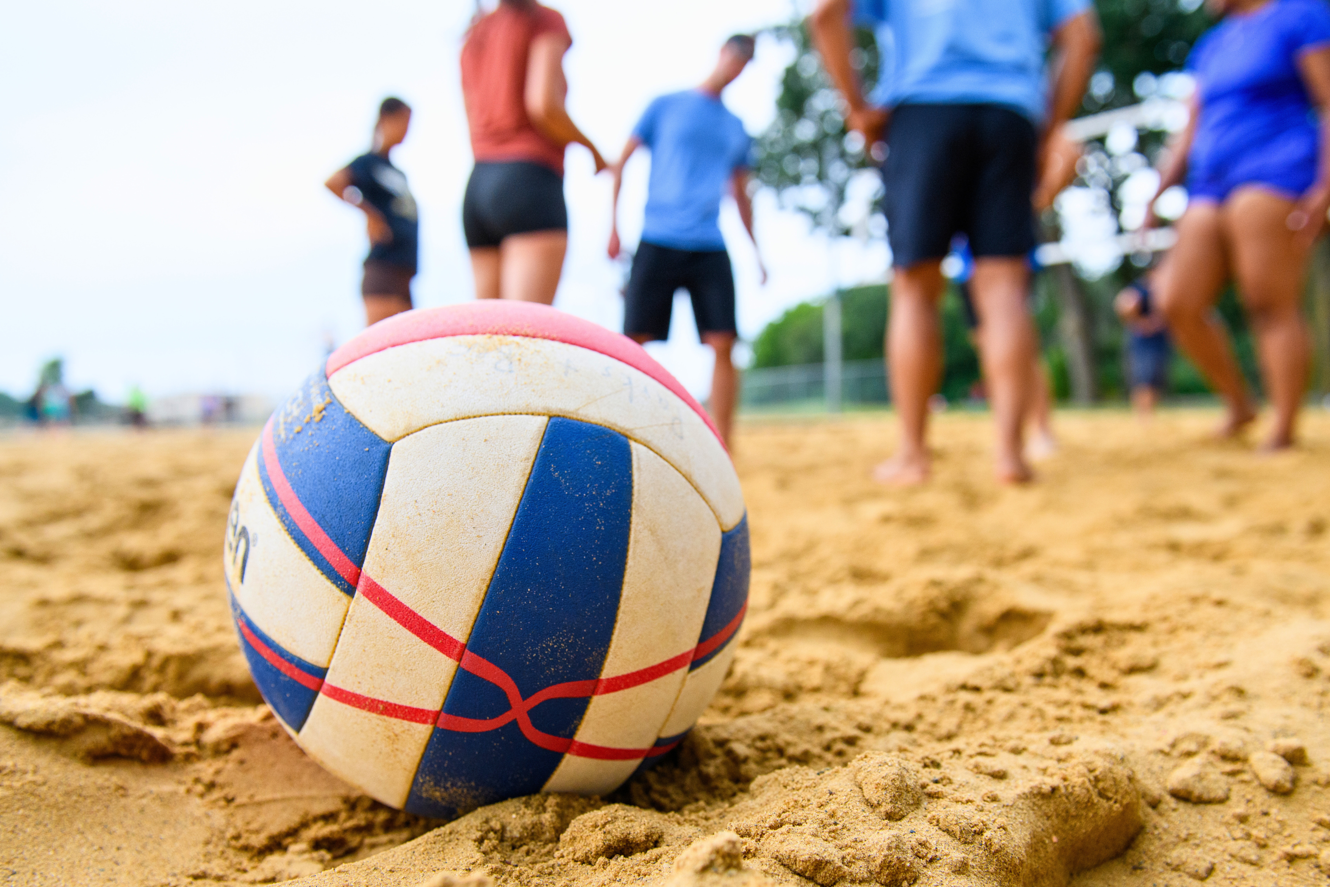 a close up view of a volleyball in the sand with players in the background
