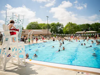 Silver Lake Pool on opening day, with community members swimming and enjoying the new outdoor pool while a lifeguard watches from a chair.