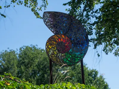 a piece of stained glass artwork in a park on a blue skied day