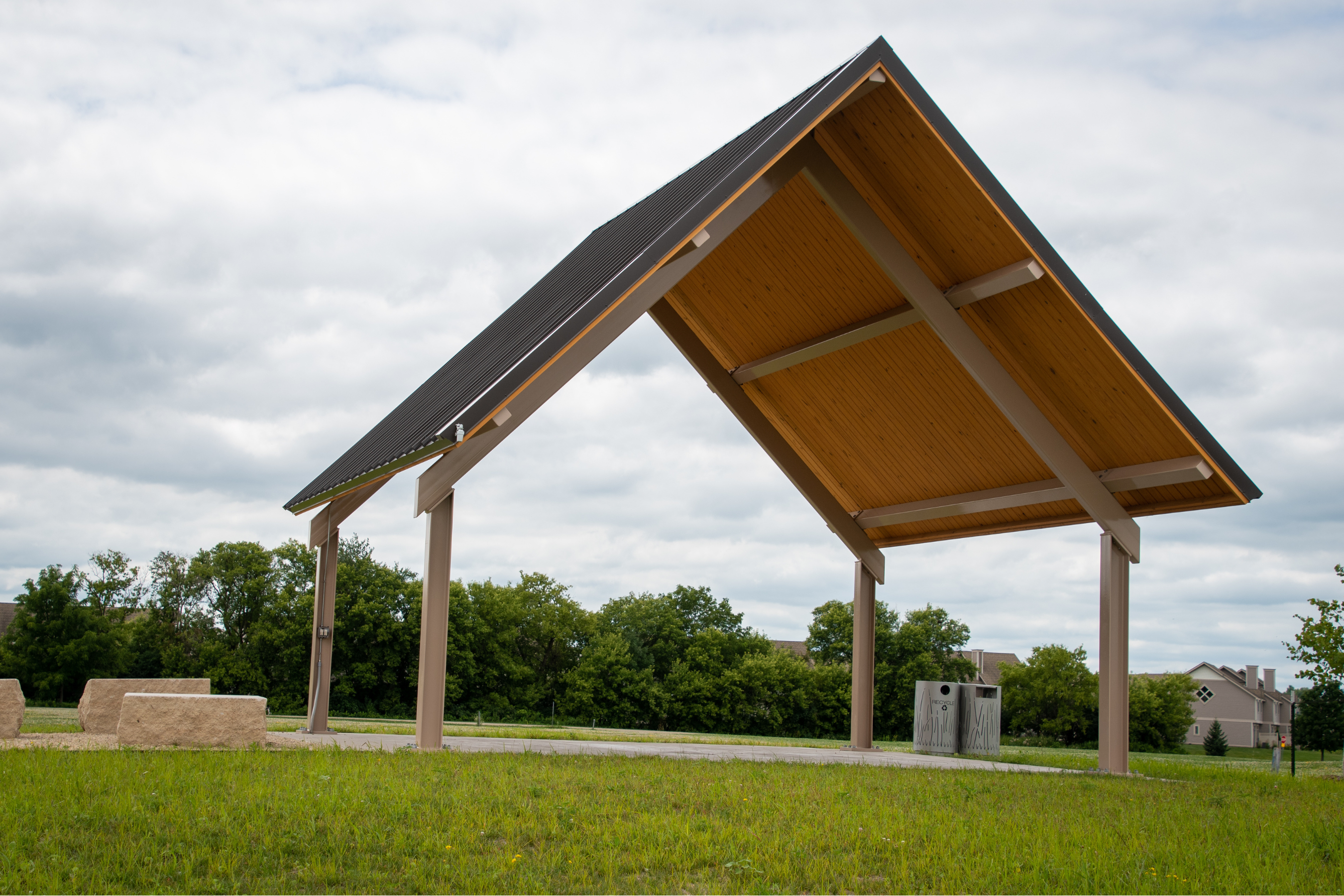 an empty picnic shelter in a field of grass on a cloudy day