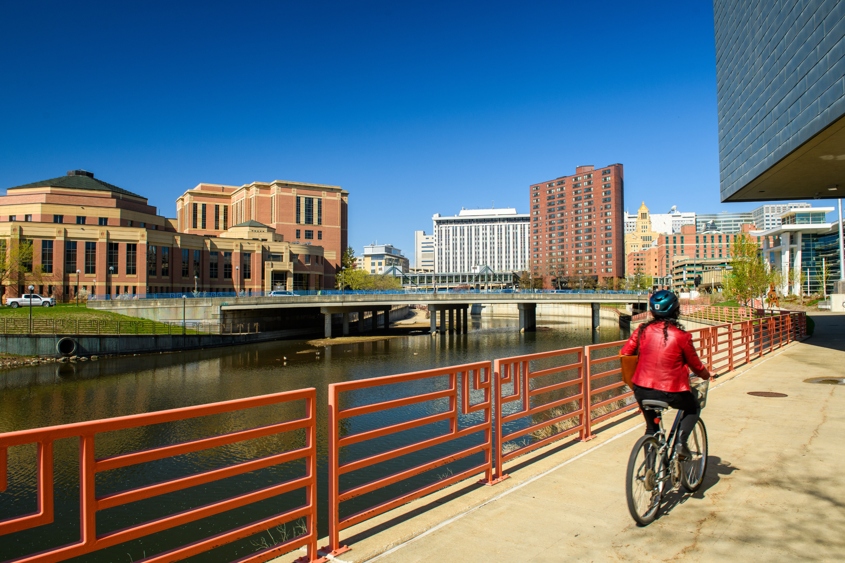 a person in a red jacket biking near the zumbro river in downtown rochester