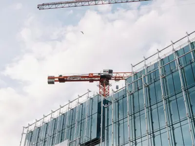 a red crane adjacent to a building under construction 