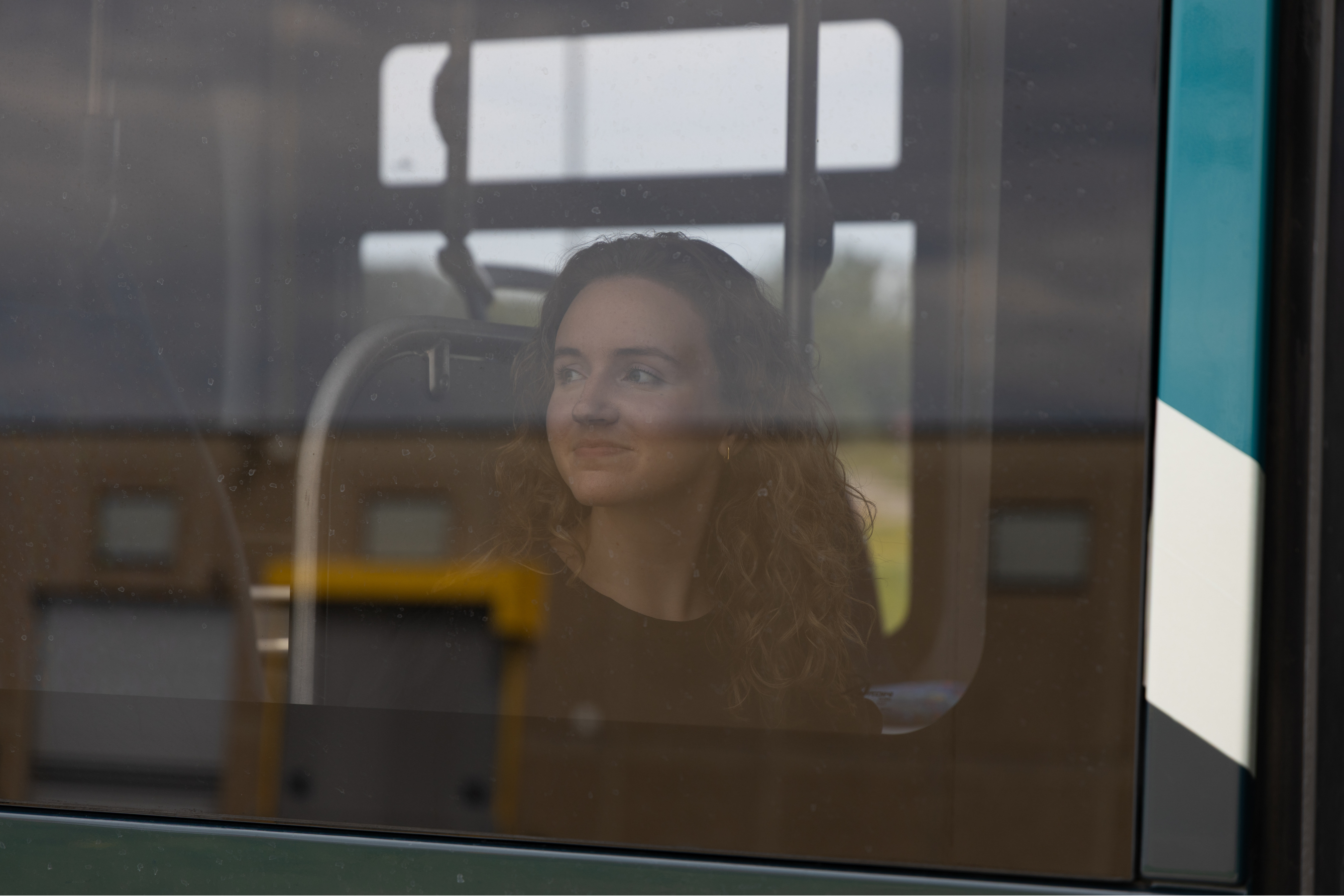 a young woman on a city bus, seen through the window from the exterior
