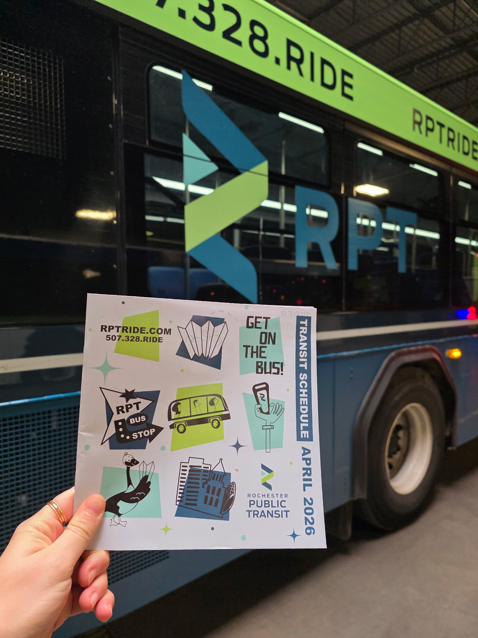 April 2026 schedule book in front of an RPT branded bus