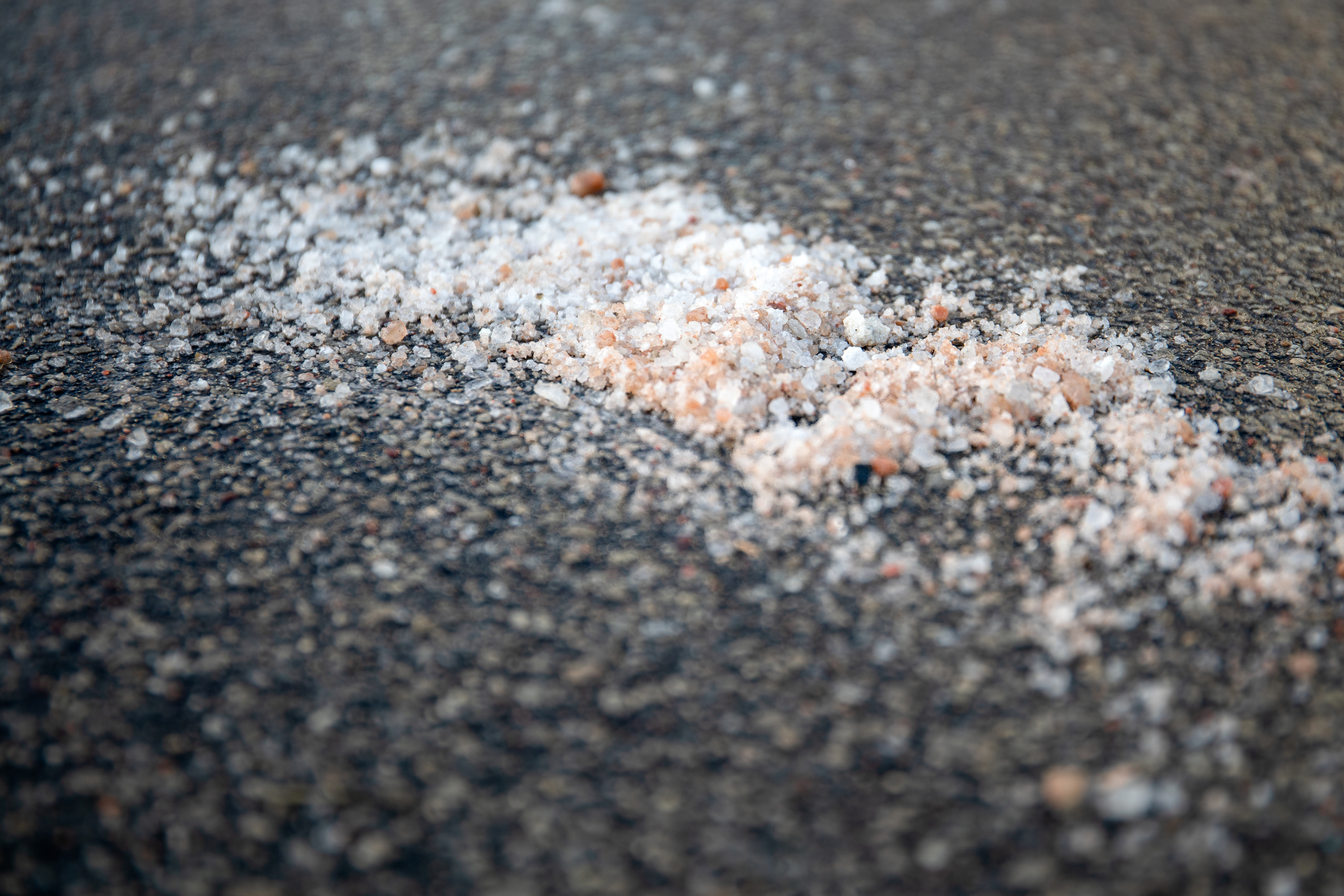 close up view of a pile of sidewalk salt on blacktop