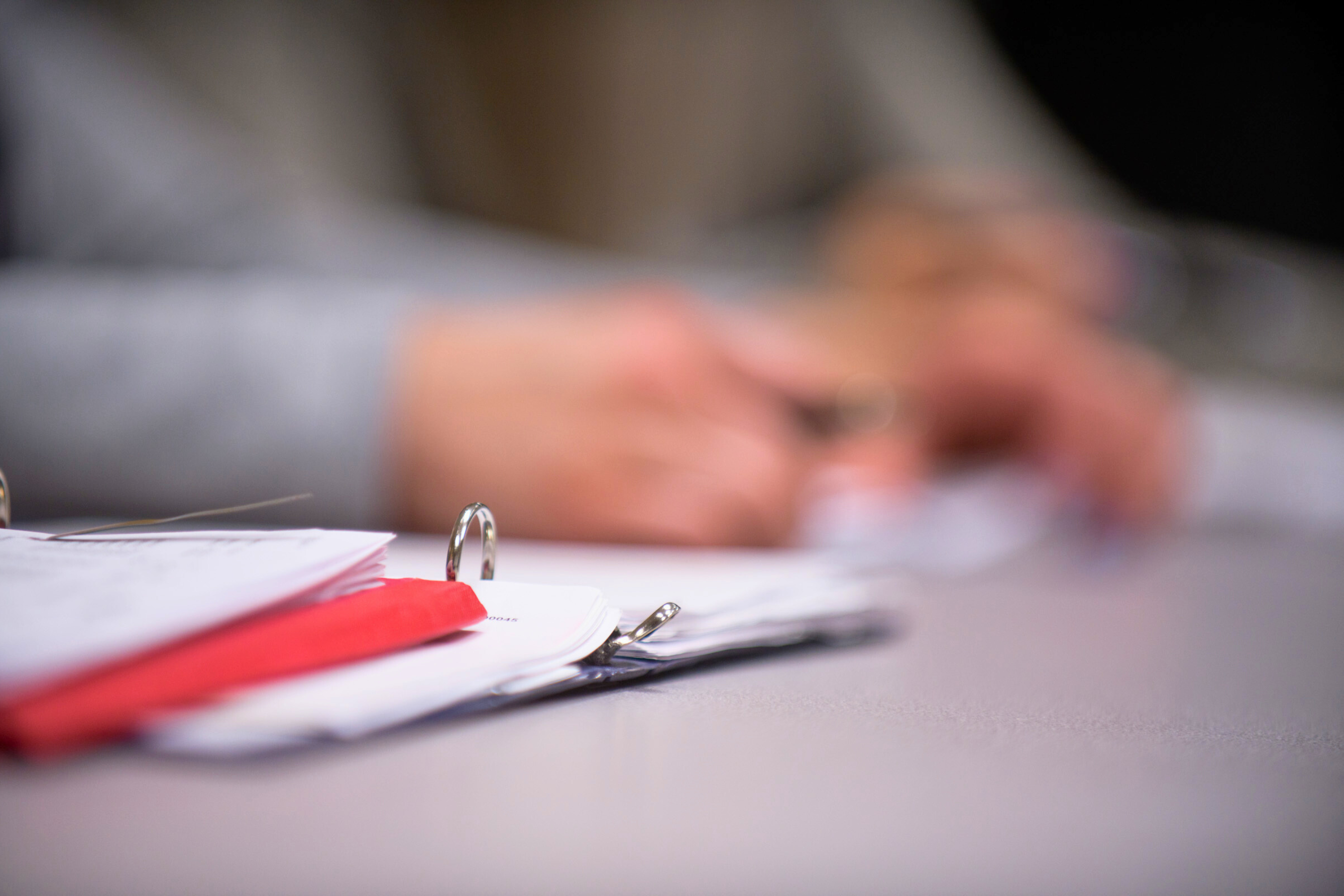 close up of a three ring binder with the content obscured and blurry hands in the background