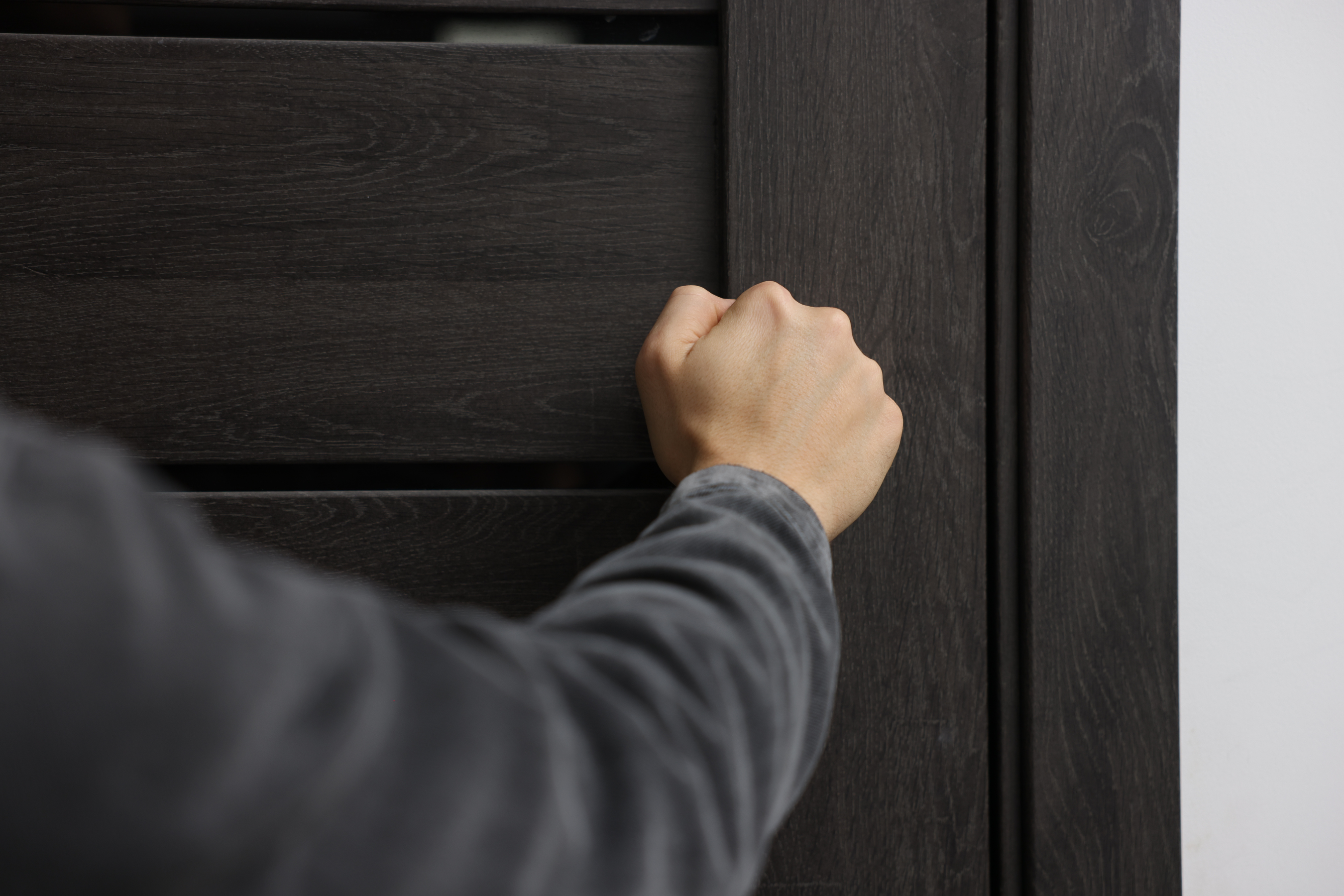 a closed fist knocking on a black door