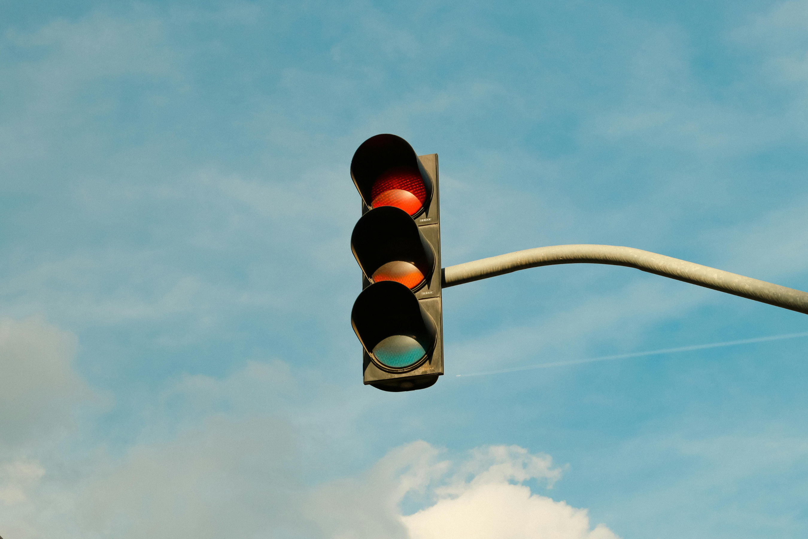a traffic light lit 'red' for stop against a cloudy blue sky