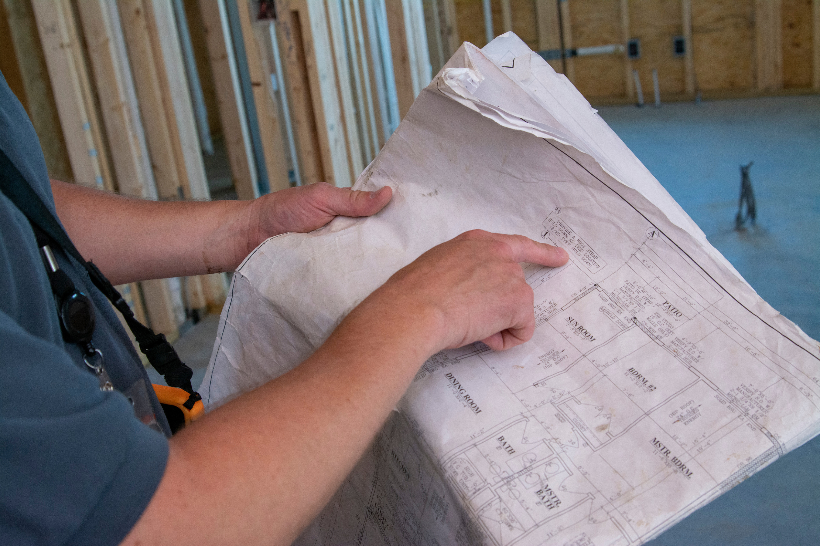 a person holding a set of blueprints for a house and pointing to a specific room