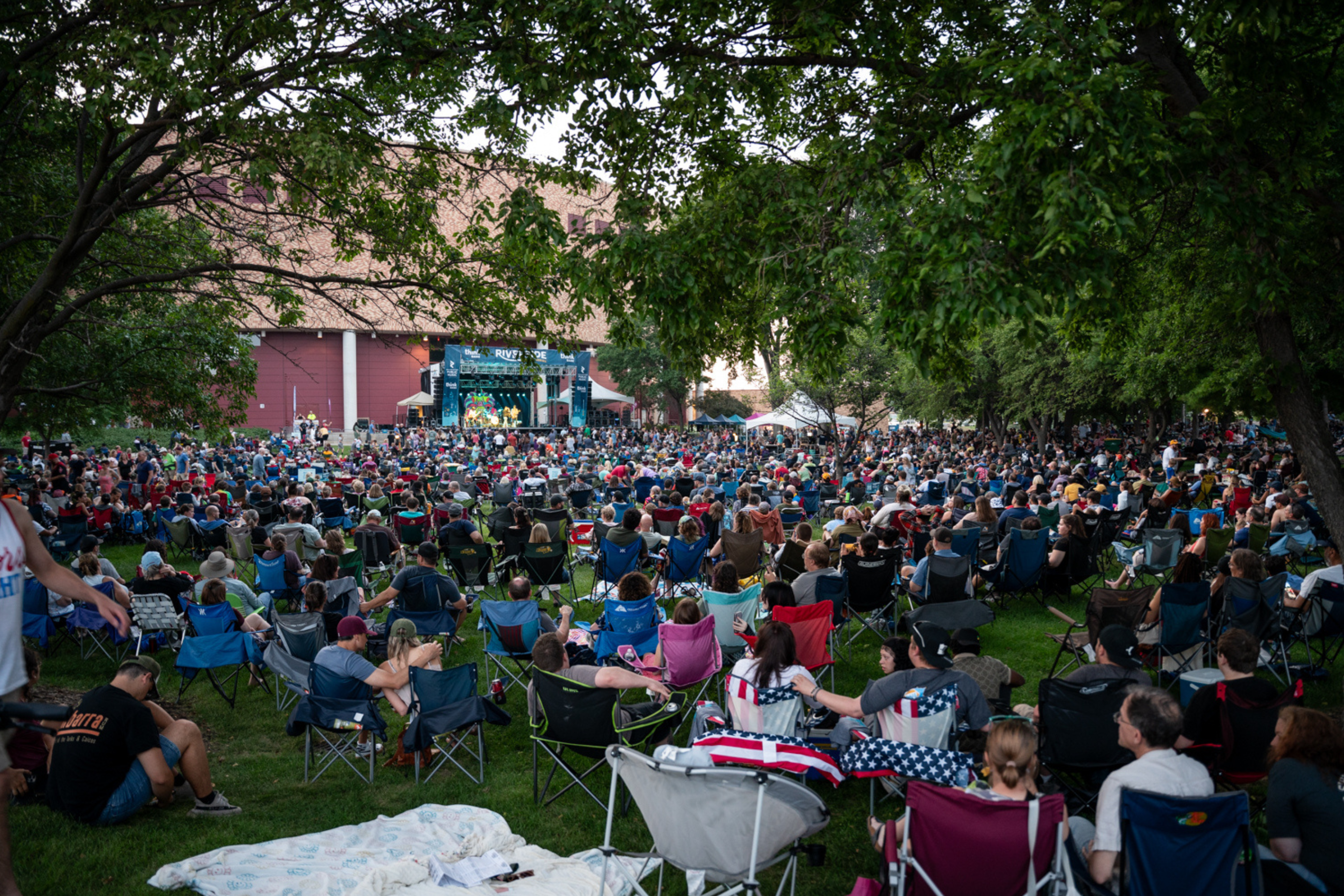 large crowd of people in lawn chairs facing a stage in the distance